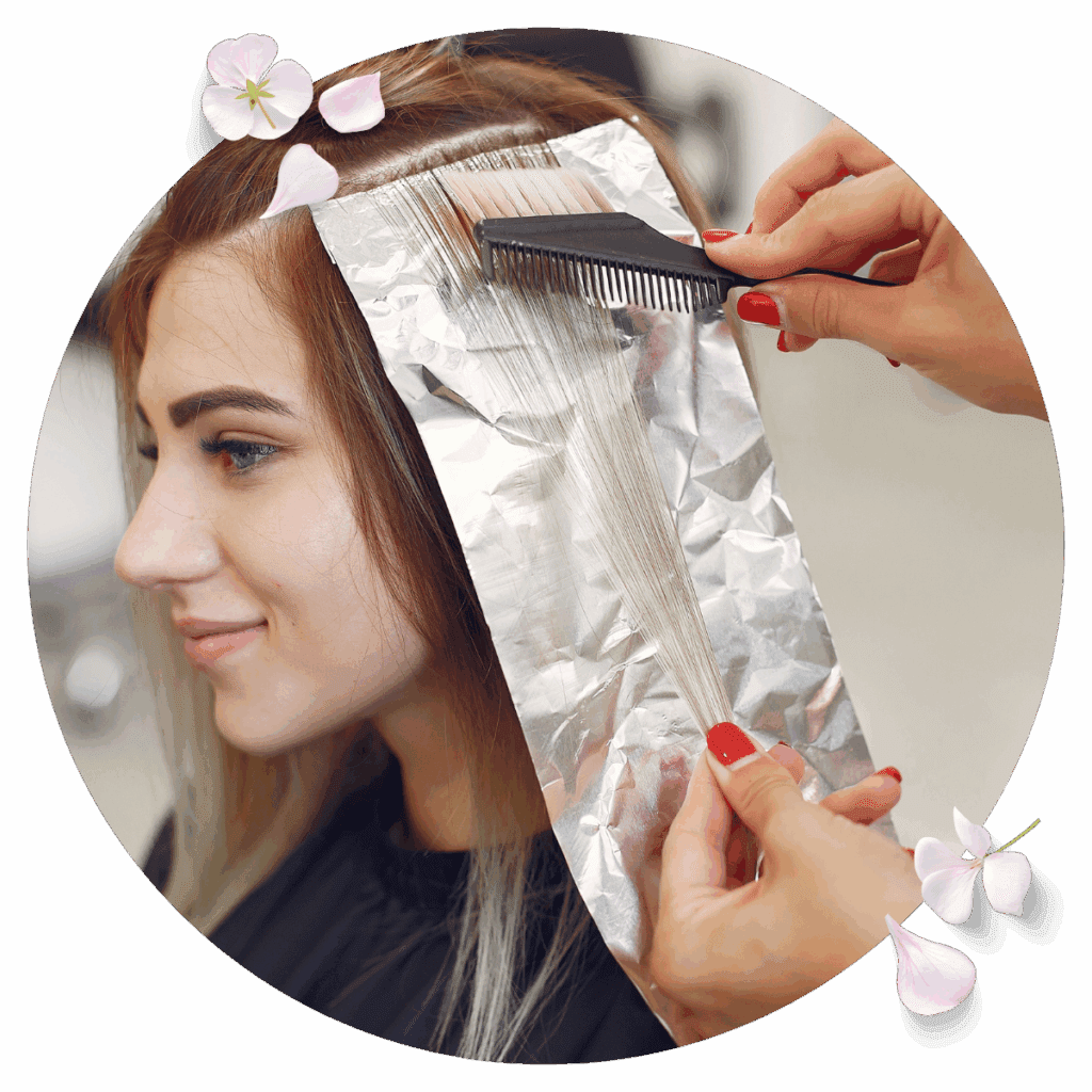 Woman at salon with foils in her hair getting her roots touched up with color